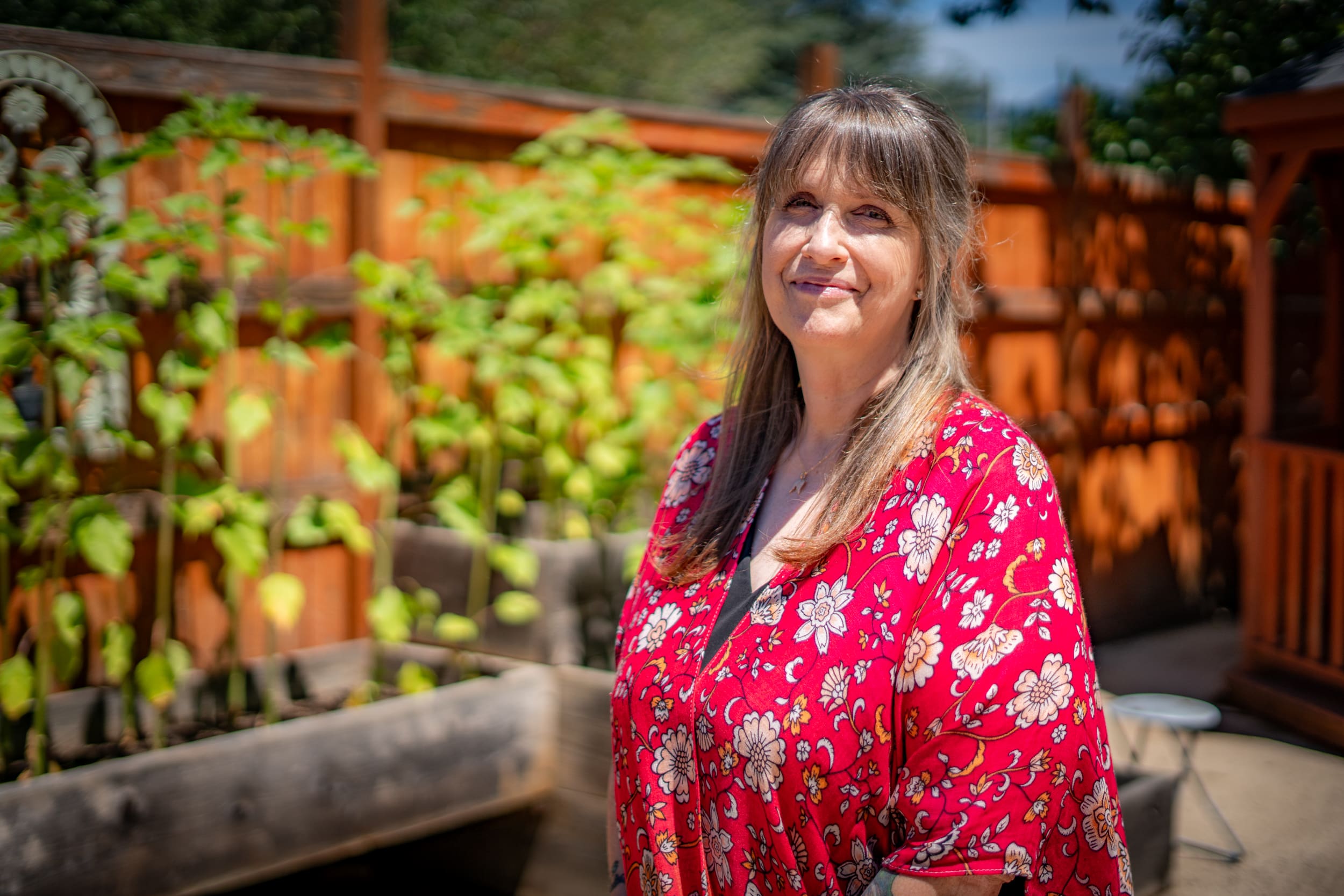 Jennifer stands in front of a fence and garden beds.